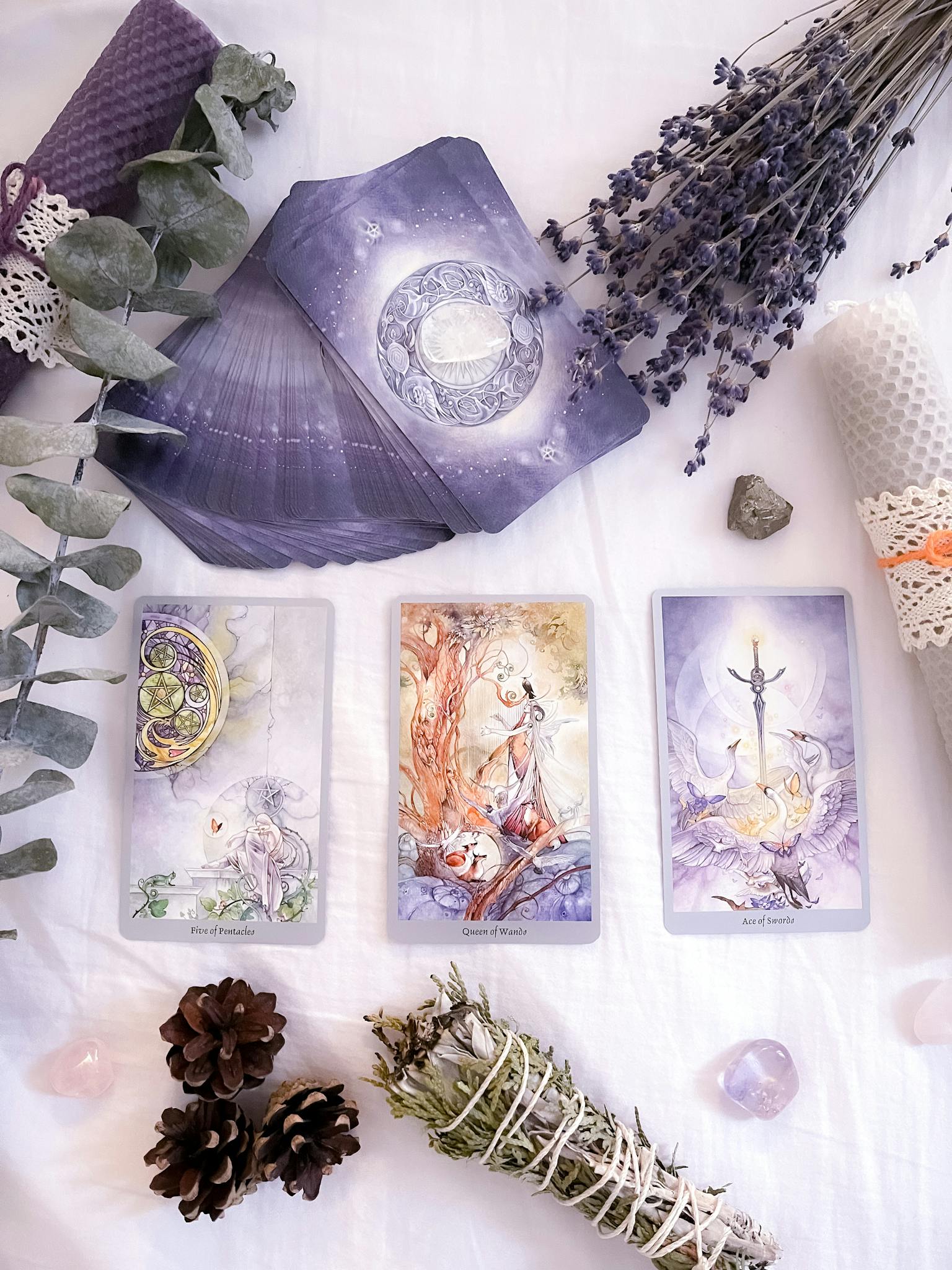 A flat lay of tarot cards surrounded by lavender, crystals, and candles, creating a mystical atmosphere.
